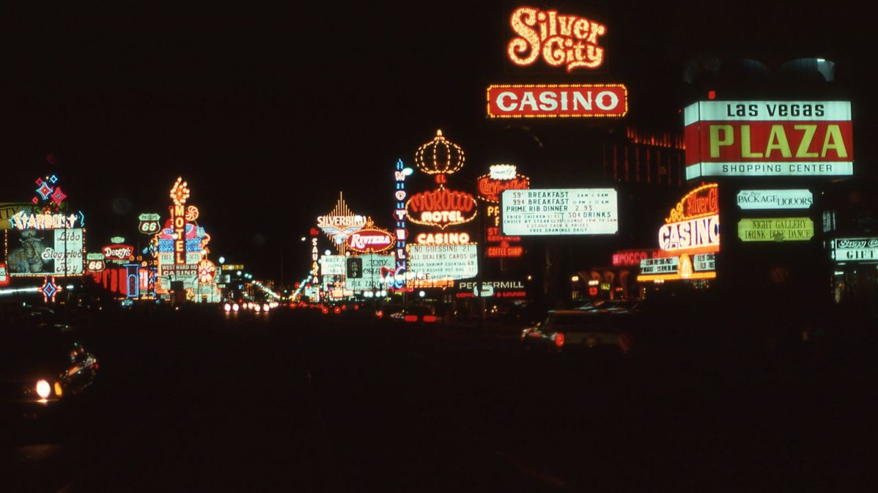 Capture the vibrant neon nightlife of vintage Las Vegas with iconic casinos and signs illuminating the cityscape.